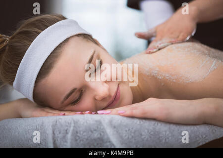 La donna che giace a estetista durante lo zucchero esfoliante massaggio scrub Foto Stock