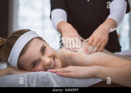 La donna che giace a estetista durante lo zucchero esfoliante massaggio scrub Foto Stock