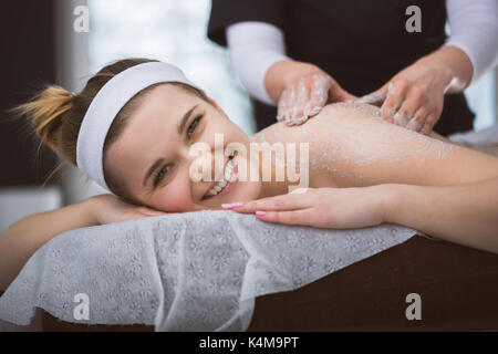 La donna che giace a estetista durante lo zucchero esfoliante massaggio scrub Foto Stock