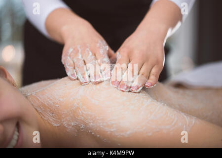 La donna che giace a estetista durante lo zucchero esfoliante massaggio scrub Foto Stock