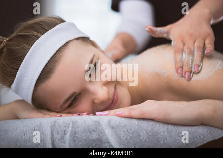 La donna che giace a estetista durante lo zucchero esfoliante massaggio scrub Foto Stock