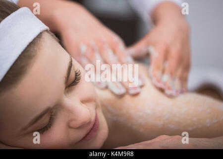 La donna che giace a estetista durante lo zucchero esfoliante massaggio scrub Foto Stock