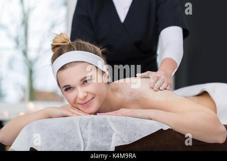 Donna in spa durante scrub al sale di trattamento di bellezza Foto Stock