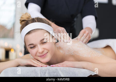 Donna in spa durante scrub al sale di trattamento di bellezza Foto Stock