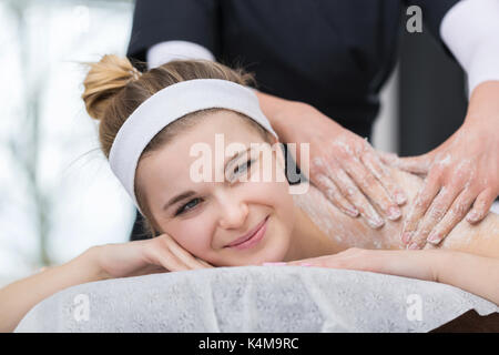 Donna in spa durante scrub al sale di trattamento di bellezza Foto Stock