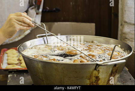 Friggere le ciambelle con olio in un mercato, cucina dettaglio, dessert Foto Stock