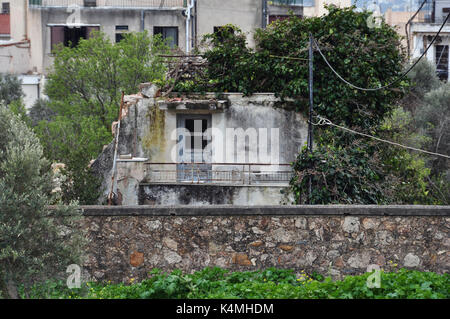 Vecchia casa abbandonata recuperato dalla natura. Urbano e rovinare la pianta infestata da erbacce. Foto Stock