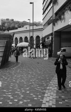 Athens, Grecia - 24 aprile 2015: l'uomo parlando al telefono cellulare e la folla di persone in piazza Monastiraki sotto l'acropoli nel centro di Atene, Grecia. Foto Stock