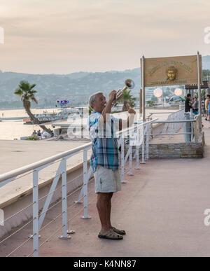 Un uomo gioca un sassofono in pubblico in Juan les Pins, Francia. La città ospita un famoso jazz festival ogni anno in estate. Foto Stock