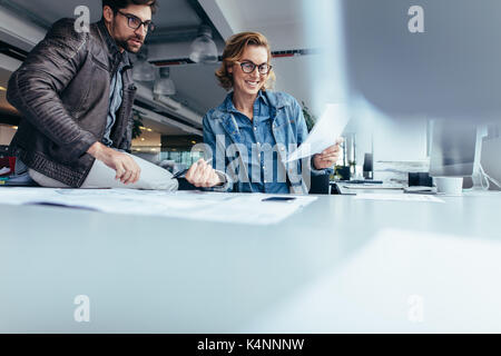 Due architetti che lavorano sul piano di costruzione in ufficio. Happy business partner di lavoro insieme alla scrivania. Foto Stock