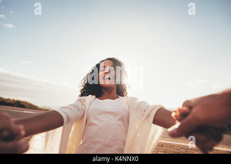 POV shot di sorridere donna africana la filatura con il suo fidanzato. Femmina ridere tenendo le mani del suo ragazzo e divertirsi. Foto Stock