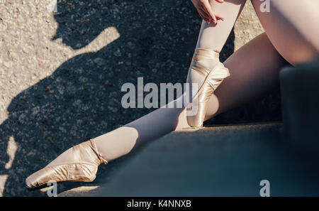 Primo piano della ballerina seduti all'aperto. Ballerina indossando scarpe di pointe seduti sulle scale. Foto Stock