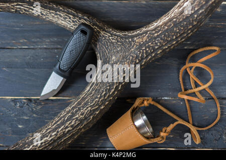 Piccolo coltello da caccia e un bicchiere in una custodia di pelle. Il corno di cervo. Foto Stock