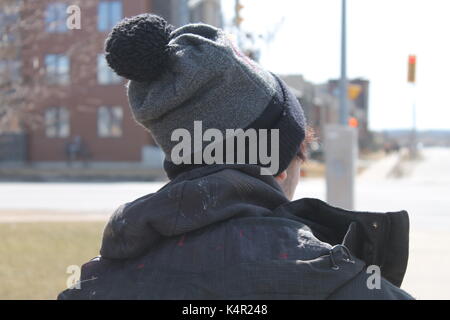 Un amico che indossa un cappello da cuoco di colore rosso/hat con un pom pom nella stagione autunnale e una giacca invernale per mantenere lo stesso caldo nella città di Barrie, ontario, Canada Foto Stock