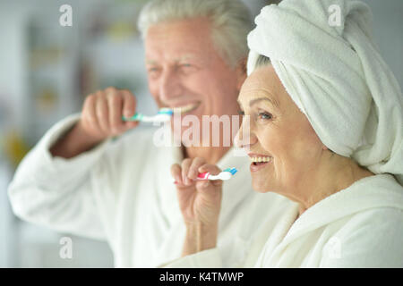 Felice coppia senior in accappatoi bianchi la spazzolatura dei denti Foto Stock