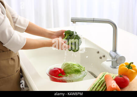 Donna giapponese il lavaggio della verdura in cucina Foto Stock