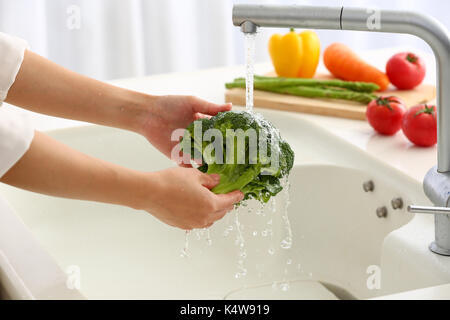 Donna giapponese il lavaggio della verdura in cucina Foto Stock