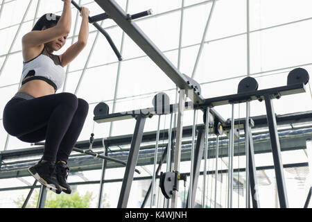 Giovane donna esecuzione di esercizio con la macchina nel centro fitness. atleta femminile della formazione in palestra. sporty ragazza asiatica di lavoro nel club salute. Foto Stock