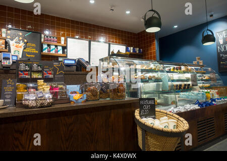 Starbucks Coffee display contatore con prodotti, torte, pasticcini e acquista in mostra a55 Starbucks Coffee shop Northop Hall, Flintshire, Galles Foto Stock