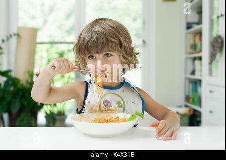 Ritratto di un simpatico ragazzo facendo un pasticcio mentre mangi la pasta per il pranzo Foto Stock