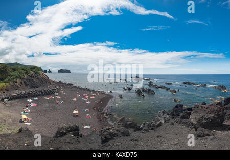 Persone in spiaggia, bagno di sole su spiaggia di sabbia nera vulcanica. Rocce sulla costa di Mosteiros, Isola di Sao Miguel, Azzorre, Portogallo Foto Stock