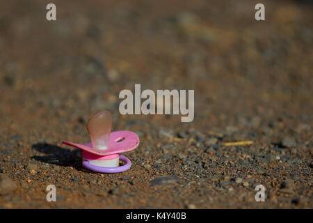 Rosa succhietto bambino giacente a terra. Foto Stock