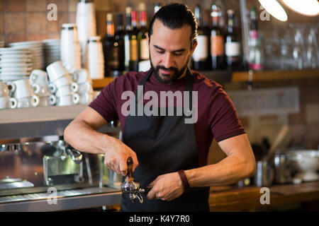 Barista uomo facendo espresso al bar o caffetteria Foto Stock