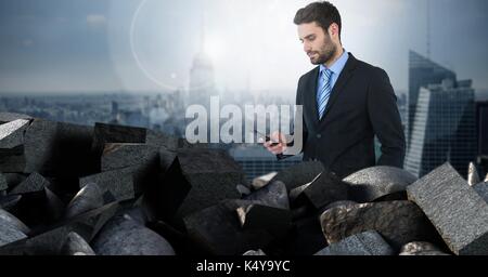 Composito Digitale di mattoni scuri in pila con imprenditore tenendo il telefono sulla città Foto Stock