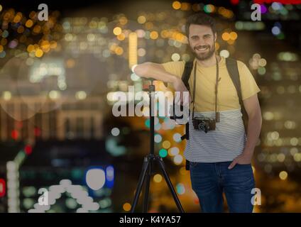 Composito Digitale del fotografo felice resto sul cavalletto di fronte alla città di notte ( con luci sfocate) e bokeh uovere Foto Stock