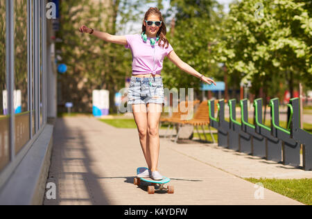 Felice ragazza adolescente in tonalità a cavallo su longboard Foto Stock