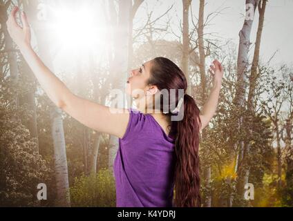 Composito Digitale dei bracci di donna in aria contro sfocata alberi con flare Foto Stock