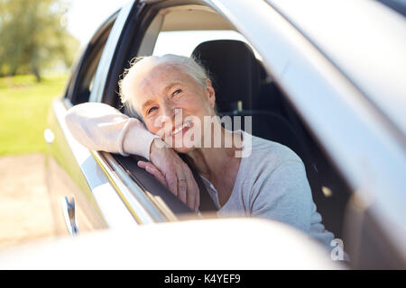 Viaggio, viaggio e il vecchio concetto di persone - happy senior donna alla guida in auto con la finestra aperta Foto Stock