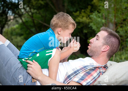 Figlio seduto sullo stomaco dei suoi padri Foto Stock