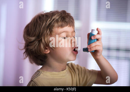Boy utilizzando l'asma inalatore per trattare malattie infiammatorie, dispnea, tosse e di tenuta al torace e mancanza di respiro. allergia al concetto di trattamento. Foto Stock