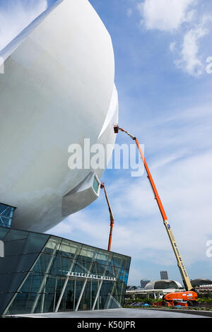 Il marina bay sabbia, Singapore - 9 Maggio 2015 : operaio è dipinto il al di fuori di artscience museum di Singapore in piedi nel cestello del braccio di articolazione l Foto Stock