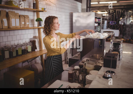 Giovane cameriera disponendo tazze al contatore nel coffee shop Foto Stock