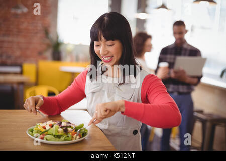 Felice giovane donna mangiare fresche insalate sane a tavola in coffee shop Foto Stock