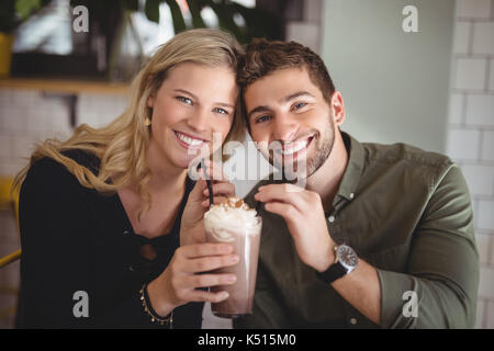 Ritratto di giovane sorridente giovane azienda dessert freschi in vetro presso la caffetteria Foto Stock