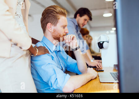 Supervisione di un collega durante il lavoro in ufficio Foto Stock