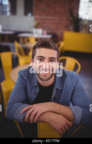 Ritratto di sorridere bel uomo seduto su una sedia al coffee shop Foto Stock