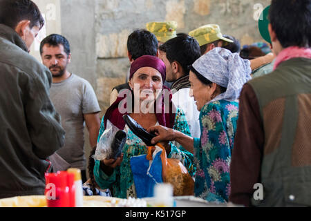 Donna afghana che vende scarpe al mercato del sabato / mercato dell'amicizia tagico-afghano a Khorugh, capitale di Gorno-Badakhshan in Tagikistan Foto Stock