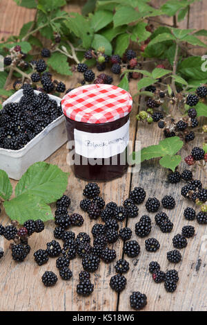 Rubus fruticosus. In casa confettura con una cestella di foraged more e Rovo foglie su un tavolo di legno in settembre. Regno Unito Foto Stock