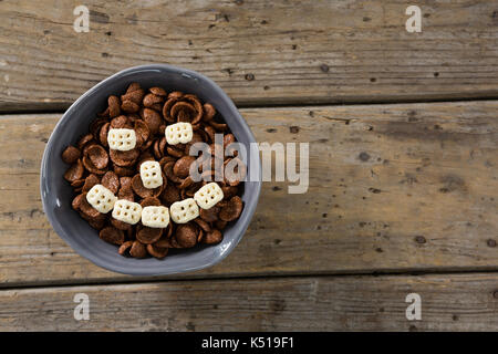 Cornflakes al Cioccolato con cereali a nido d'ape formando Smiley face nella ciotola sul tavolo di legno Foto Stock