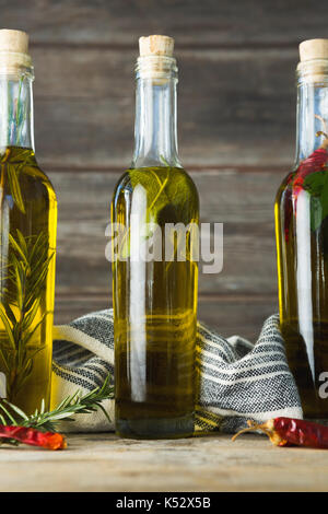 Olio di oliva bottiglie con erbe e spezie contro lo sfondo di legno Foto Stock