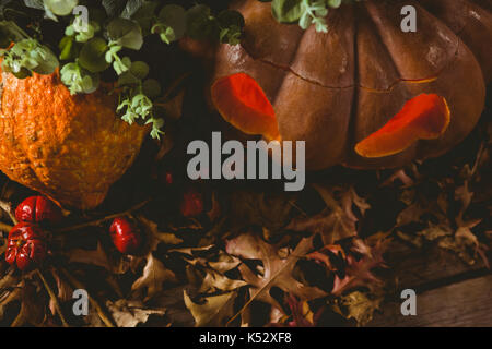 Angolo di alta vista di jack o lanterna con foglie di autunno sul tavolo durante il periodo di Halloween Foto Stock