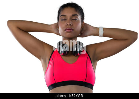 Atleta femminile con gli occhi chiusi e le mani dietro la testa contro uno sfondo bianco Foto Stock