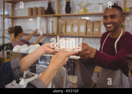 Tagliate le mani della cliente che riceve il caffè dal proprietario del maschio al cafe Foto Stock