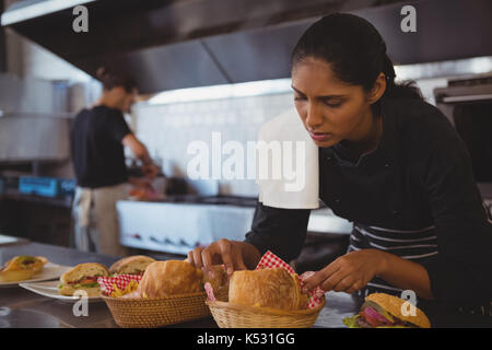 Giovane cameriera disponendo cesti con cibo a contatore in cafe Foto Stock