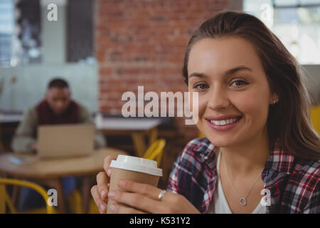 Ritratto di felice giovane donna azienda tazza di caffè presso il cafe Foto Stock