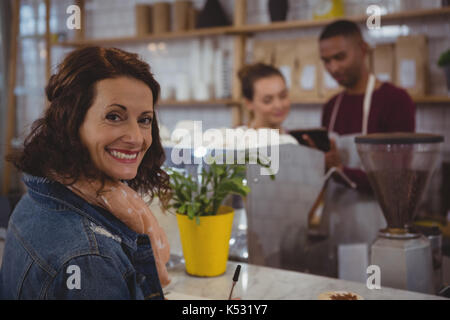 Ritratto di donna sorridente con i clienti proprietari di discutere in cafe Foto Stock